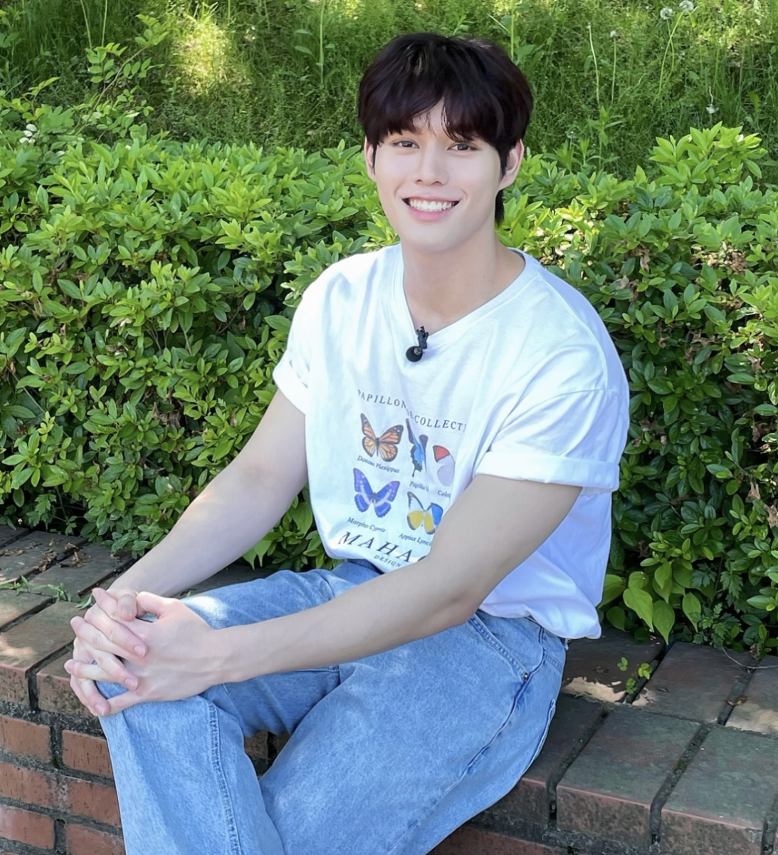 GHOST9プリンスが植え込みの前で座って微笑んでいる写真